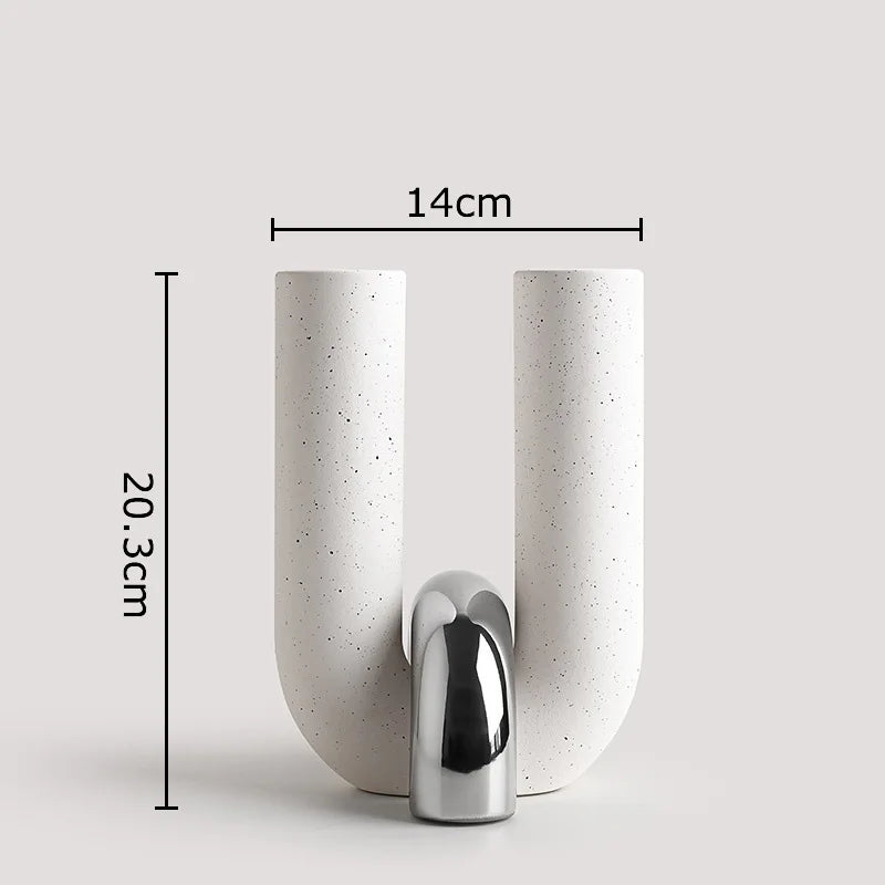 A tall, cylindrical ceramic vase with a U-shape, featuring a textured white finish and a chrome finial.