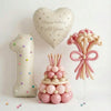 A display featuring a large number balloon, a heart-shaped birthday balloon, and a cluster of pink and cream spherical balloo