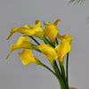 A bunch of yellow artificial calla lily stems with green leaves against a gray background.