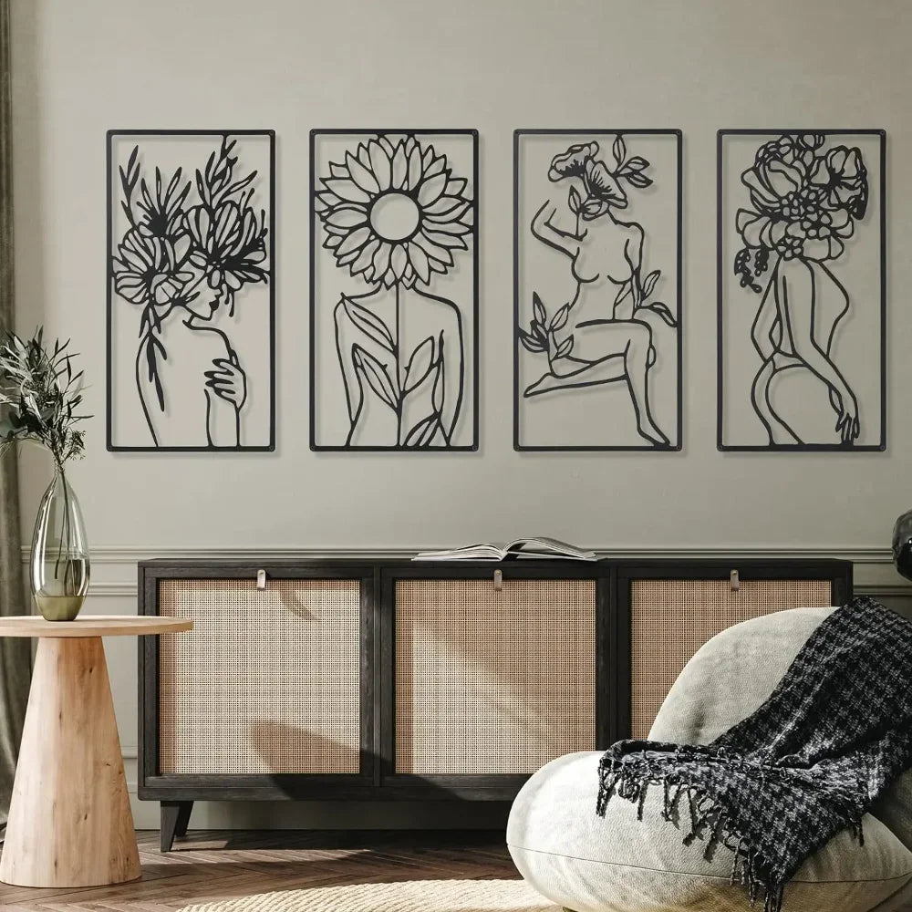 A set of four black line art prints depicting abstract female figures and floral designs displayed on a gray wall above a woo