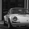 Une voiture de sport Porsche blanche et noire garée devant un bâtiment.
