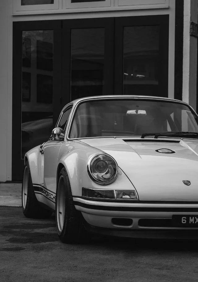 Une voiture de sport Porsche blanche et noire garée devant un bâtiment.
