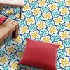 A red cushion rests on a brightly patterned floor featuring yellow and blue floral Moroccan design stickers.