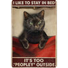 A vintage metal sign featuring a black cat looking intensely at the viewer with green eyes and text that reads I like to stay