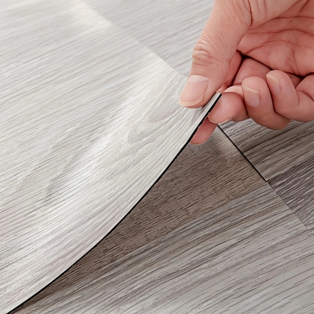 A hand is peeling a sheet of self-adhesive wood grain decor stickers from a backing sheet.