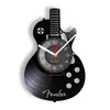 A black wall clock shaped like a vinyl record, featuring a guitar design and clock face.