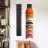 Organizador vertical para gorras de béisbol en degradado naranja y marrón montado en pared blanca.