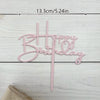 Pink acrylic birthday cake topper with elegant script lettering on a white wooden background.