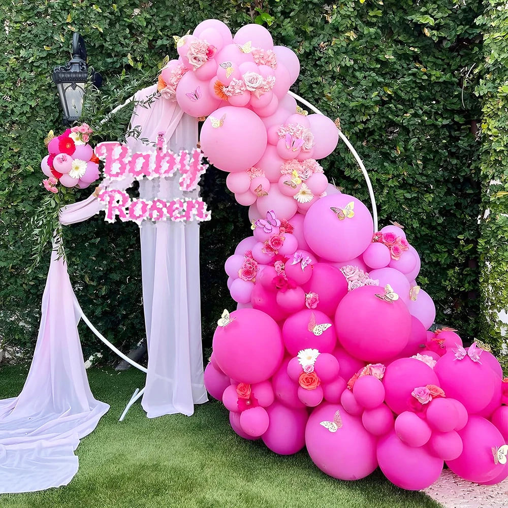 A large balloon arch display featuring pink and purple latex balloons for a baby shower or party backdrop.