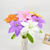 A hand-crocheted bouquet of artificial lily flowers in various shades of pink, purple, orange, and white.
