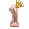 A rose gold foil balloon shaped like the number one with a gold crown on top