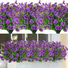 A dense arrangement of purple and pink artificial flowers in green foliage displayed in a vase.