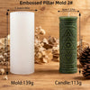 A white pillar candle mold and a green embossed pillar candle are shown on a wooden surface.