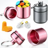 A pink pill organizer with a clear window and a silver cap, shown alongside various components and a keyring.