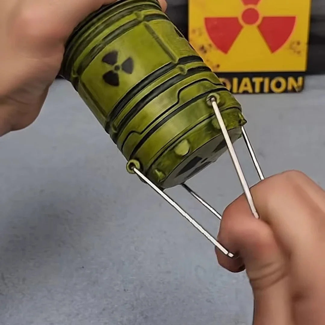 A hand holds a miniature nuclear reactor lantern with a green glow and protruding metal prongs.
