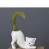 A white ceramic cartoon cat planter shaped like a reclining feline with an arched succulent plant.