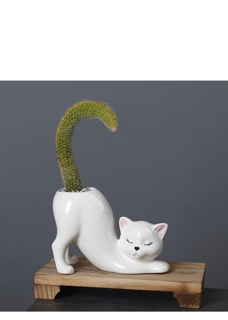 A white ceramic cartoon cat planter shaped like a reclining feline with an arched succulent plant.