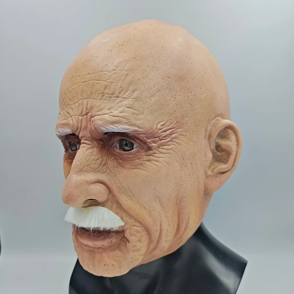A realistic latex mask of an old man with white hair and a mustache, displayed on a black stand.
