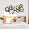 A set of four hexagon wooden floating shelves displaying decorative items above a bed.