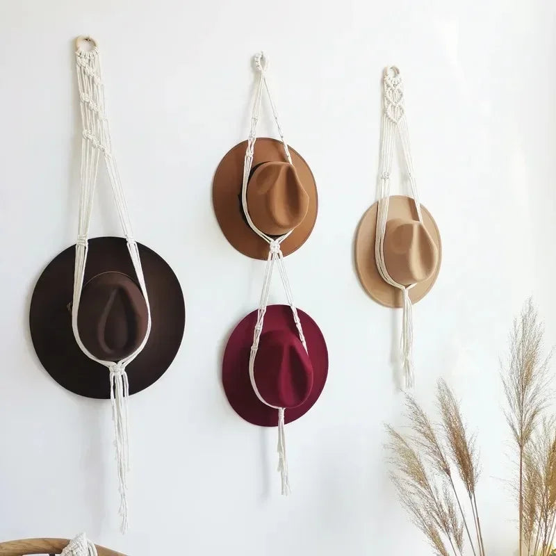 Three macrame hat organizers with wooden dowels are displayed as boho wall hangings against a white background.