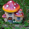 A resin mushroom house garden statue featuring a large red and white spotted toadstool roof and a small wooden house.