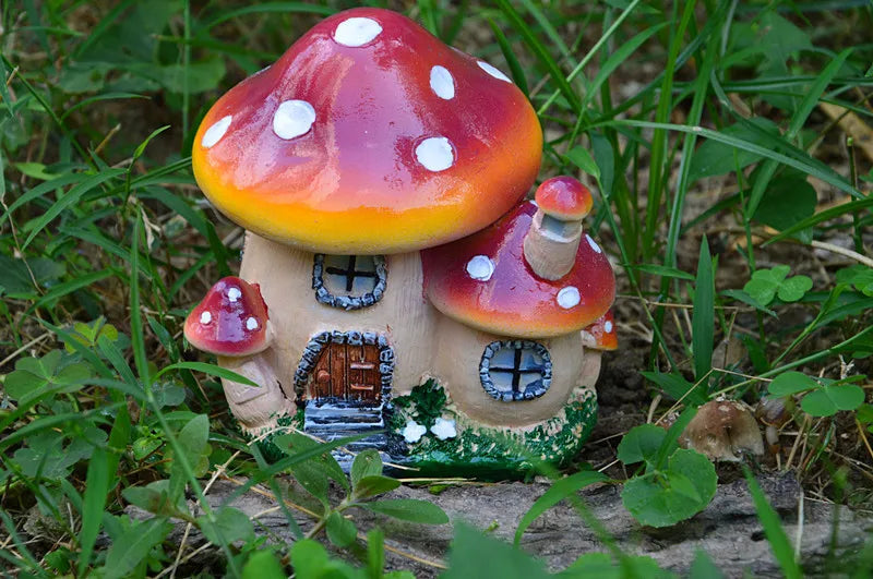 A resin mushroom house garden statue featuring a large red and white spotted toadstool roof and a small wooden house.