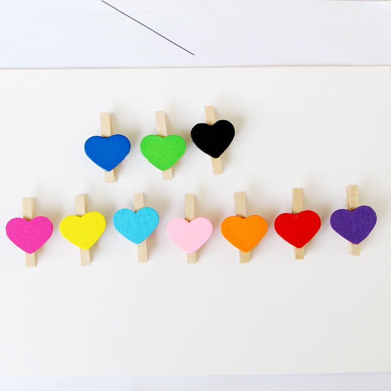 A collection of colorful heart-shaped mini wooden photo clips arranged in a row.