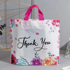 White floral thank you gift bags with pink handles and a black script message