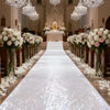 An elegant white sparkling aisle runner leading down a church aisle decorated with white flowers and chandeliers.