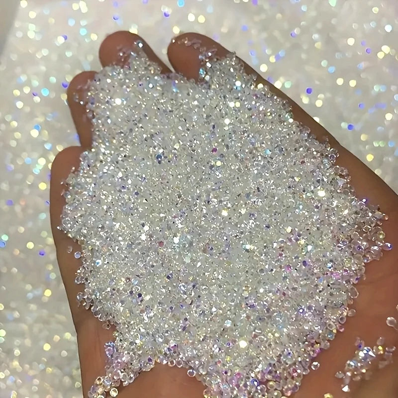 A hand holds a pile of multicolor AB glass micro beads for nail art and DIY crafts.