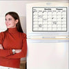 A woman stands next to a refrigerator with a monthly planner calendar visible on the door.