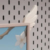 A pair of white, wing-shaped decorations are displayed against a patterned wall background.