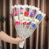 A bouquet of artificial rose soap flowers in various colors including pink, red, purple, and yellow, held by a hand.