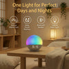 A smart device combining a sunrise alarm clock, sound machine, Bluetooth speaker, and colorful night light resting on a woode