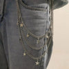 Close-up of a denim garment featuring a layered silver chain belt with small star charms.