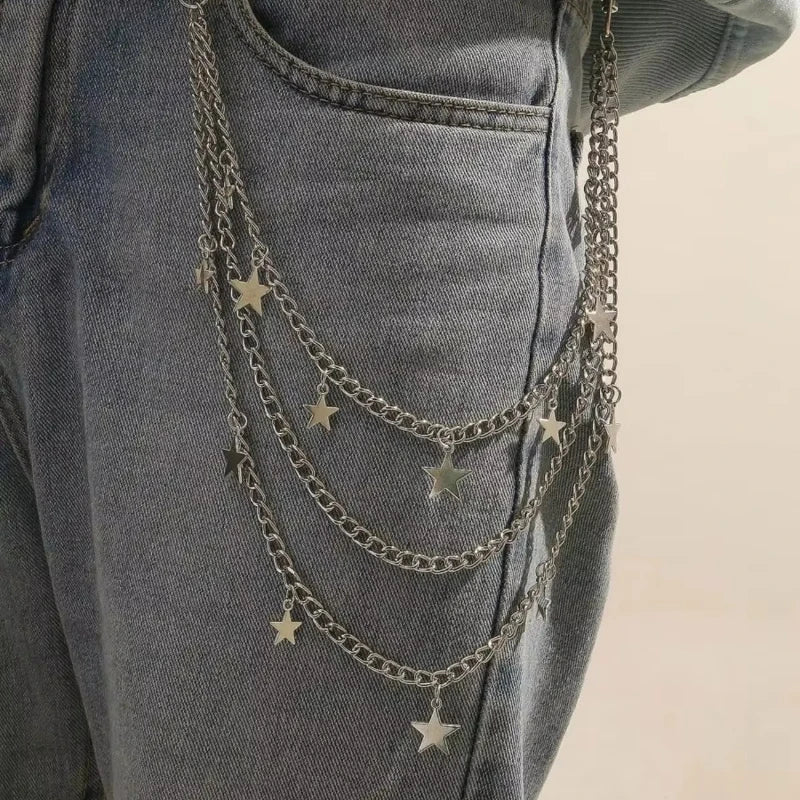 Close-up of a denim garment featuring a layered silver chain belt with small star charms.
