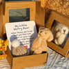 Un oso de peluche mini y una tarjeta inspiradora presentados en una caja de regalo de cartón.