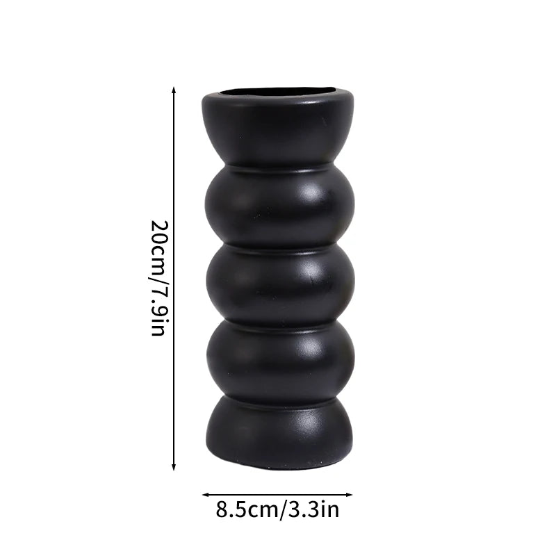Black ceramic vase with stacked, rounded segments, shown against a white background.