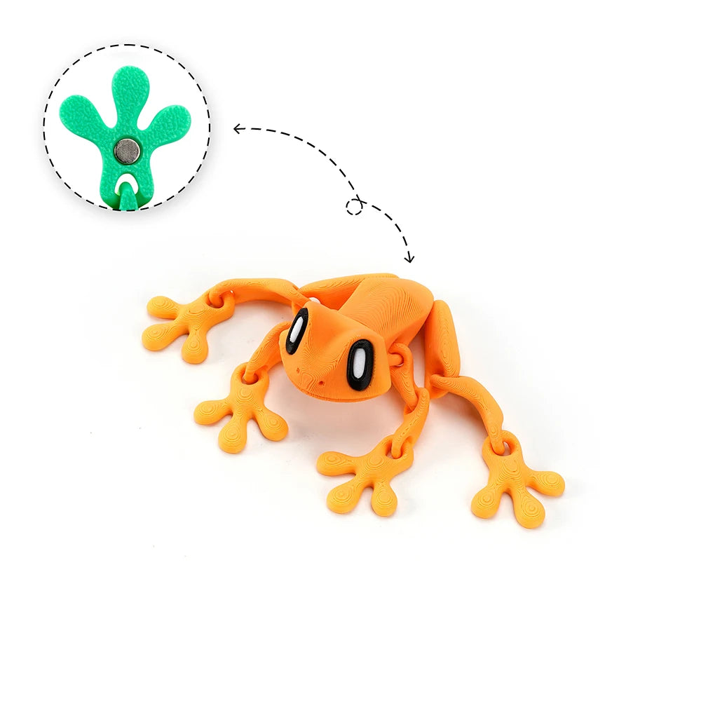An orange articulated 3D printed frog magnet with green details, shown next to its detached head.