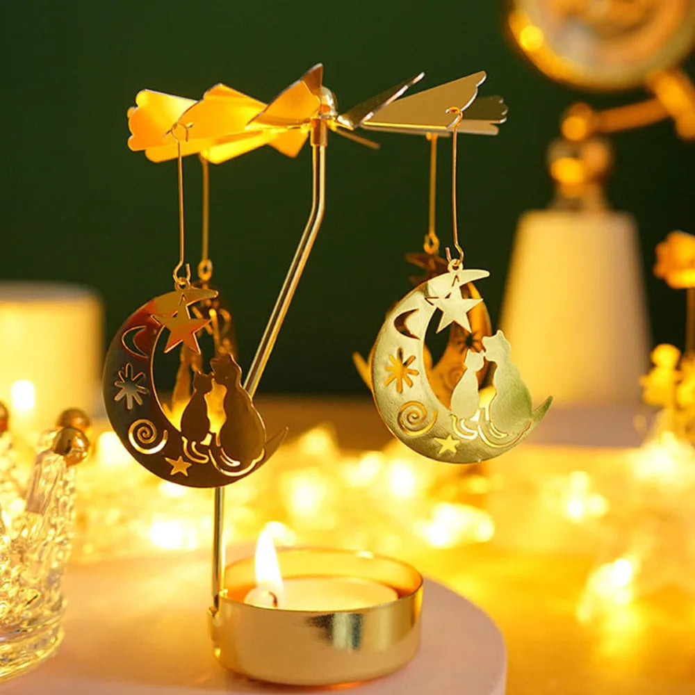 A gold rotating candle holder with a spinning carousel featuring crescent moon and star charms, set against a warm, glowing b