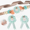 A set of floral maternity sash and corsage pins featuring blue, peach, and cream roses on a sheer ribbon.