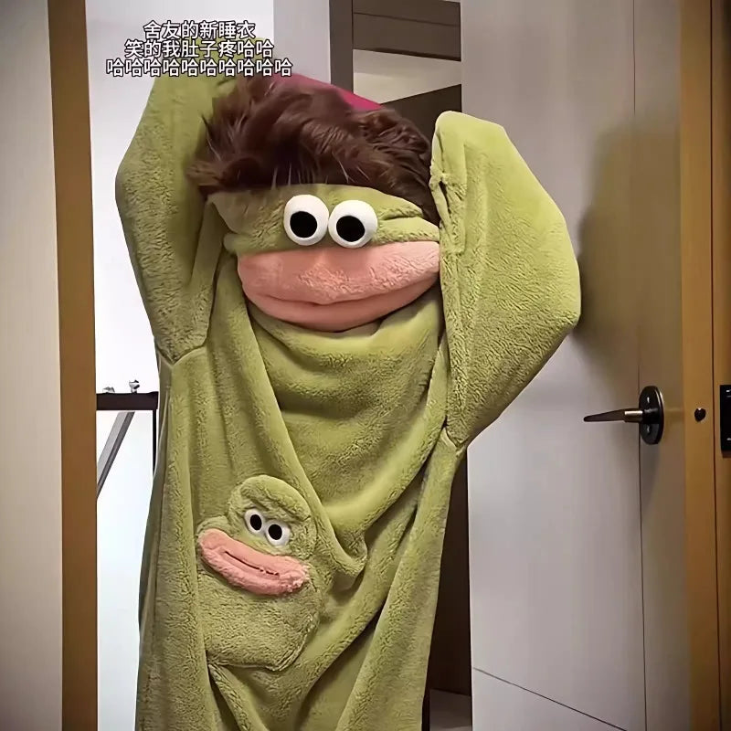 A person wearing a green fuzzy monster onesie pajama with large eyes and pink features.