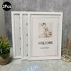 Three white photo frames displayed against a gray wall, showing a welcome message and a floral arrangement.