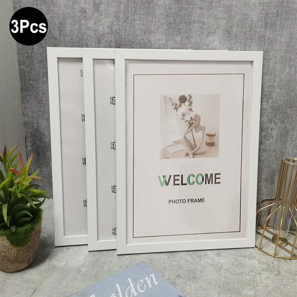 Three white photo frames displayed against a gray wall, showing a welcome message and a floral arrangement.