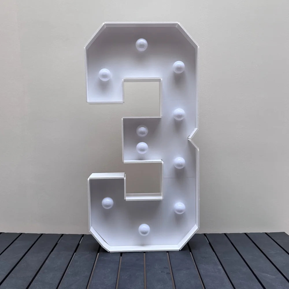 A white light-up marquee number sign displaying the number 3, mounted on a stand.