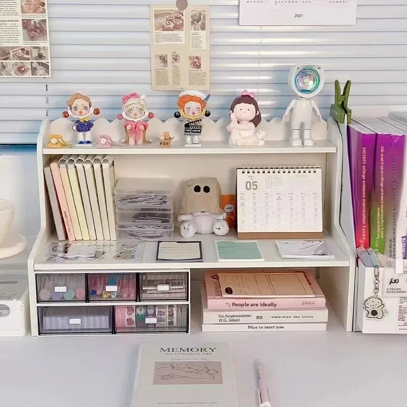 A white two-layer desktop organizer shelf displaying various stationery, small figures, and desk accessories.