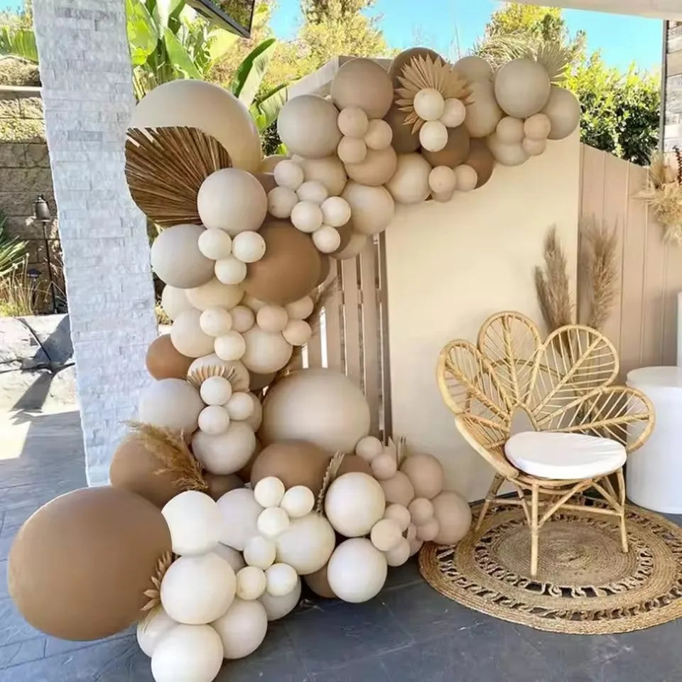 A balloon garland featuring beige, cream, and tan balloons arranged on a white wall outdoors.