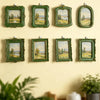 A collection of six vintage baroque resin picture frames with green ornate borders displaying landscape paintings mounted on 