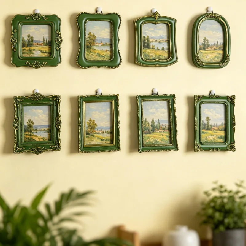 A collection of six vintage baroque resin picture frames with green ornate borders displaying landscape paintings mounted on 