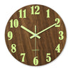 Reloj de pared de madera redondo con números y manecillas verdes que muestra la hora.